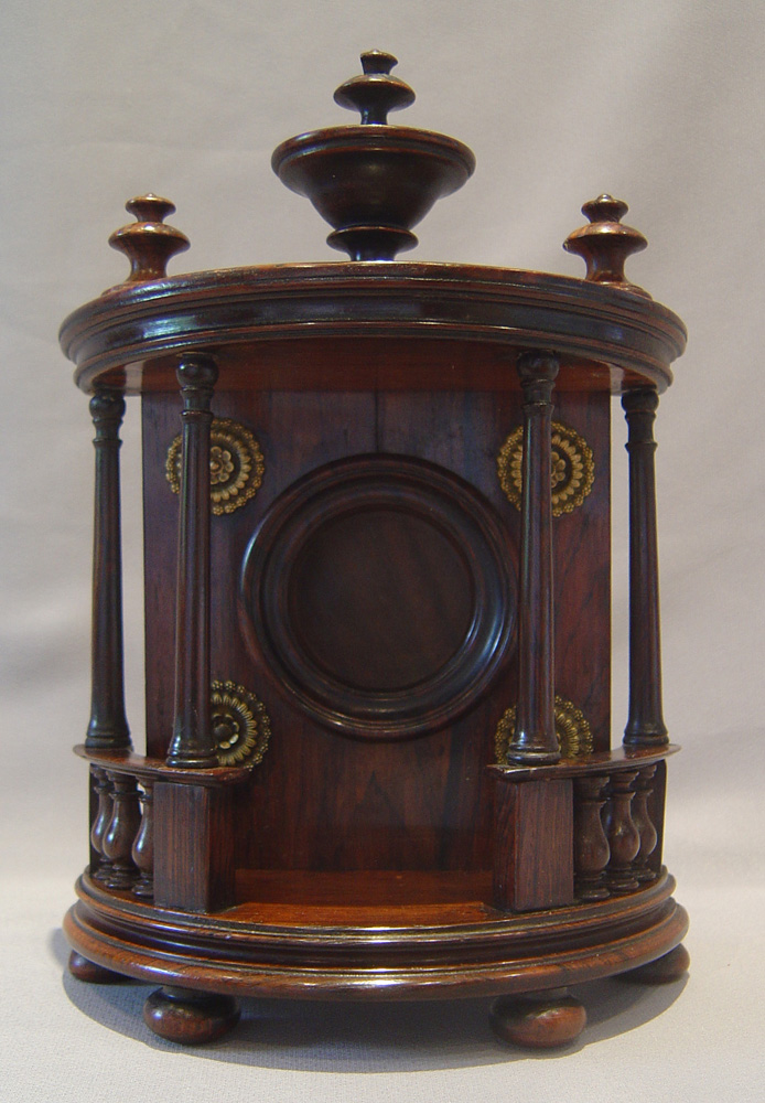Watch stand in rosewood in bow fronted bronze mounted case with columns and finials.