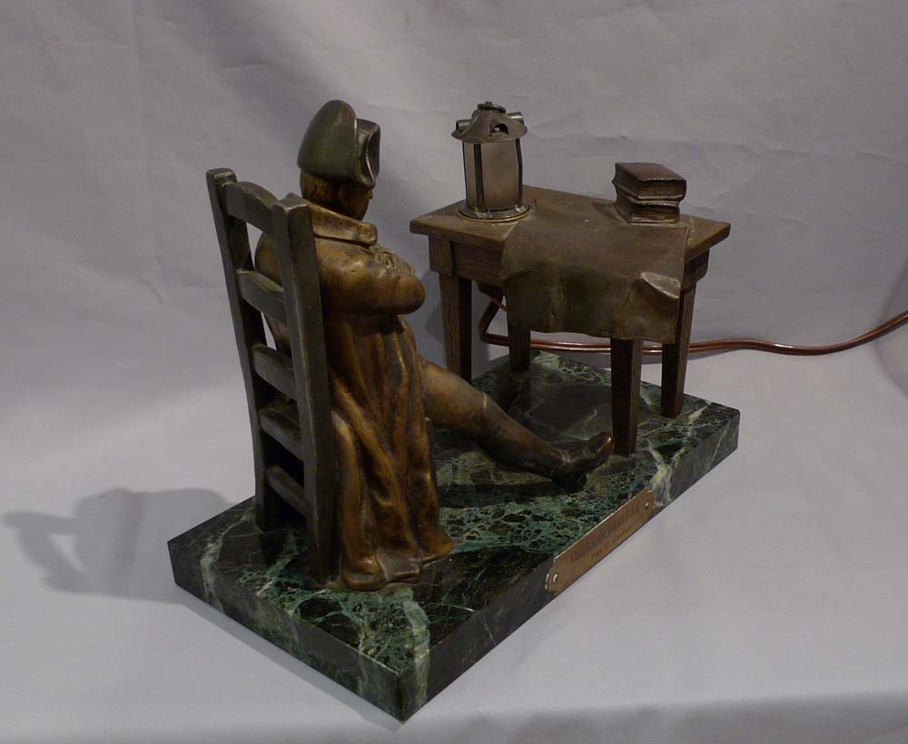 Antique Napoleon Bonaparte figural lamp showing Napoleon seated at a table.