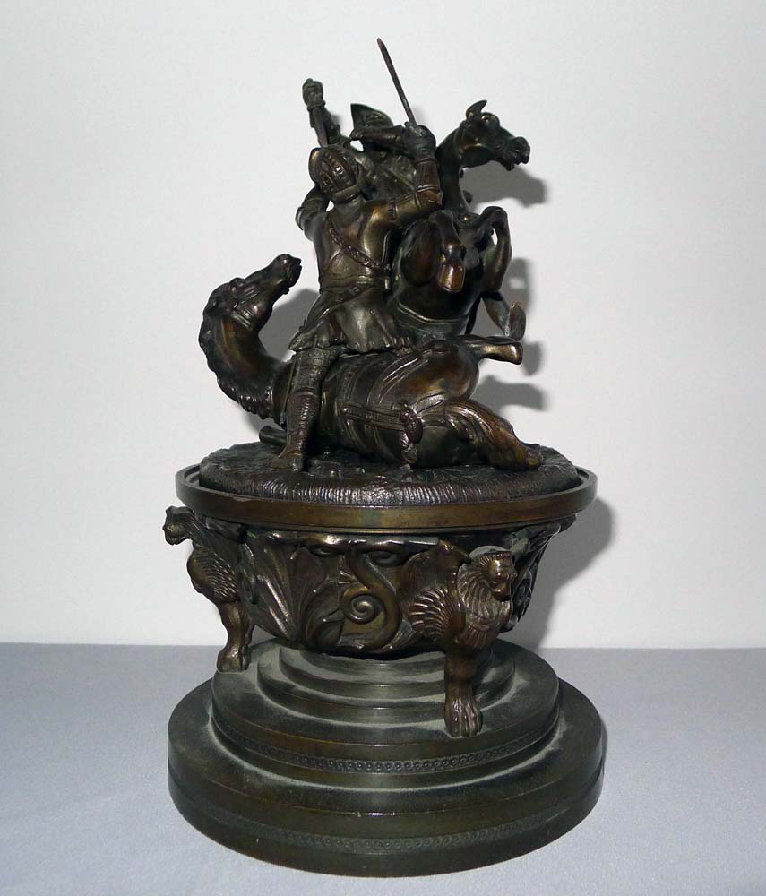 A patinated bronze figural inkwell with the detachable cover applied with Knights fighting on horses
