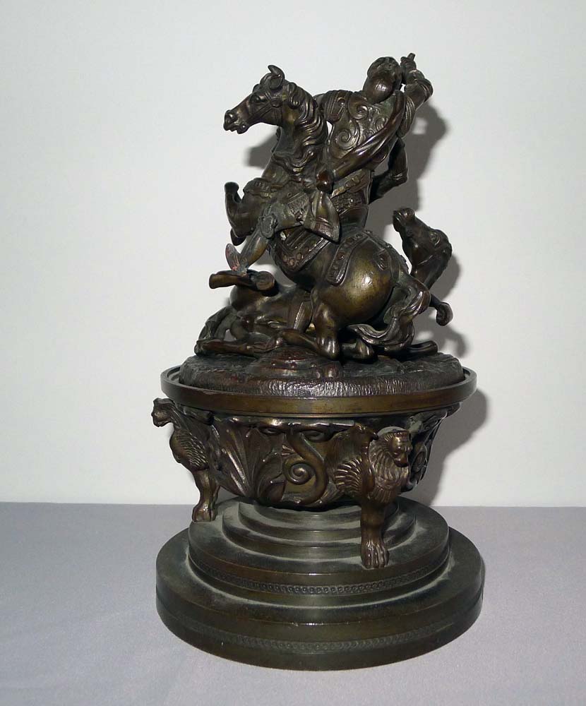 A patinated bronze figural inkwell with the detachable cover applied with Knights fighting on horses