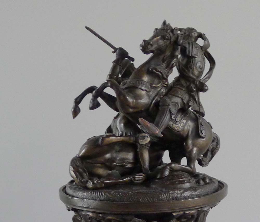 A patinated bronze figural inkwell with the detachable cover applied with Knights fighting on horses