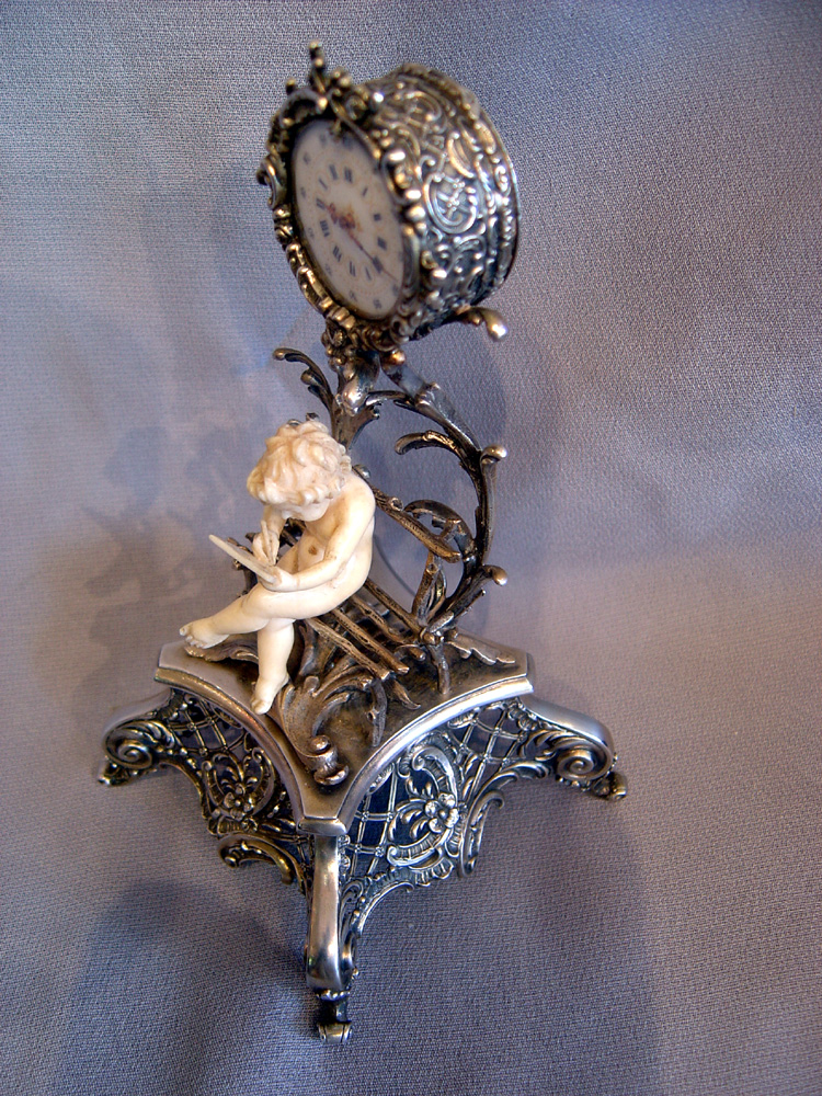 Antique Austrian silver gilt and ivory miniature clock of cupid in a bower.