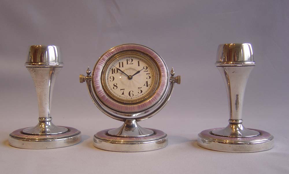 Silver and lilac guilloche enamel garniture of clock and pair of candlesticks..
