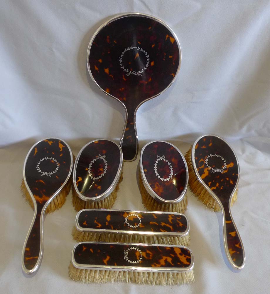 Harlequin set of tortoiseshell, silver piquer and silver brushes and mirror.