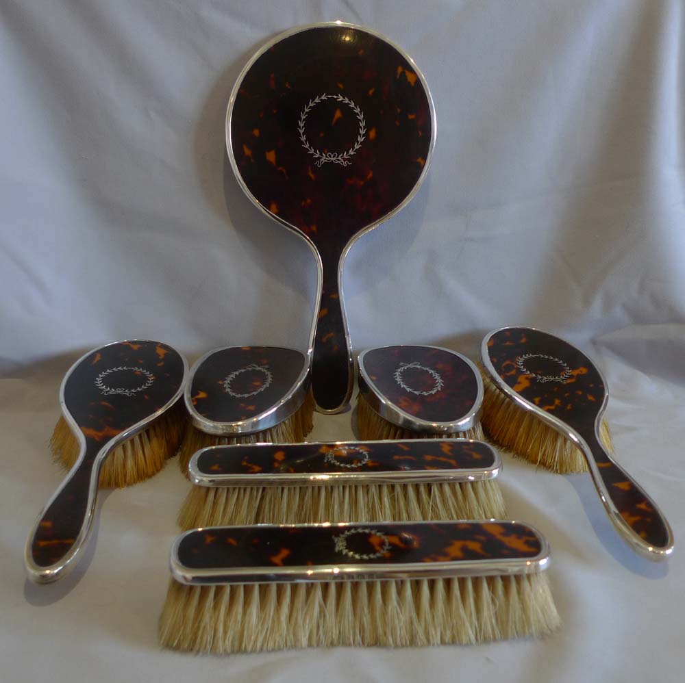 Harlequin set of tortoiseshell, silver piquer and silver brushes and mirror.