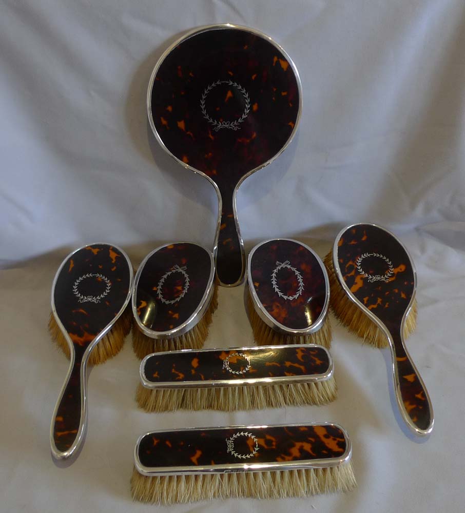 Harlequin set of tortoiseshell, silver piquer and silver brushes and mirror.