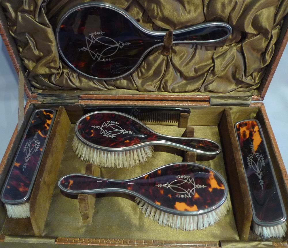 Silver and silver pique tortoiseshell hairbrushes and hand mirror in original case.