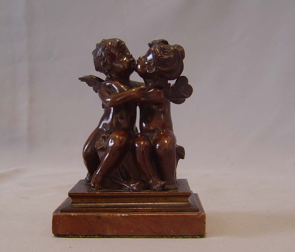 Antique French romantic bronze of winged puttae kissing set on a marble base.
