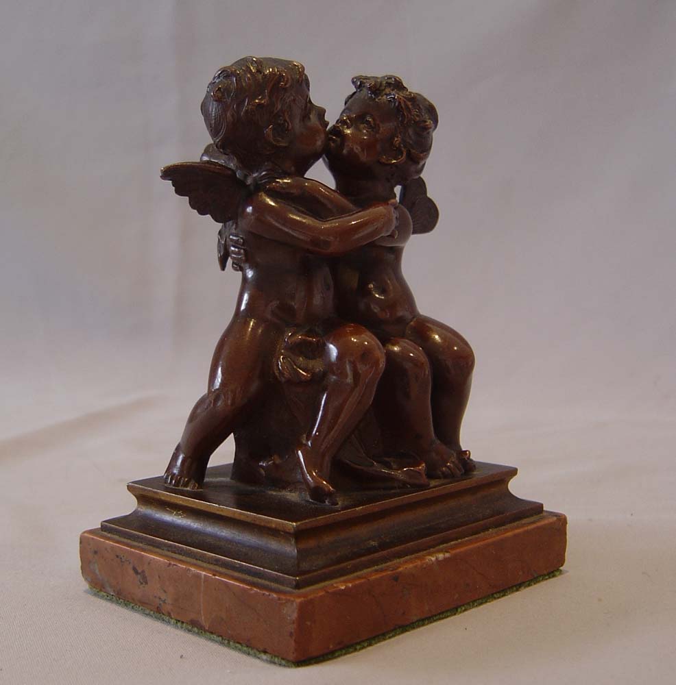 Antique French romantic bronze of winged puttae kissing set on a marble base.