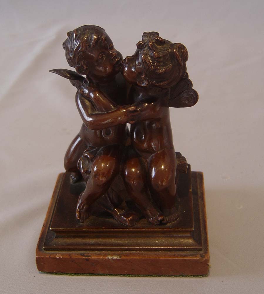 Antique French romantic bronze of winged puttae kissing set on a marble base.