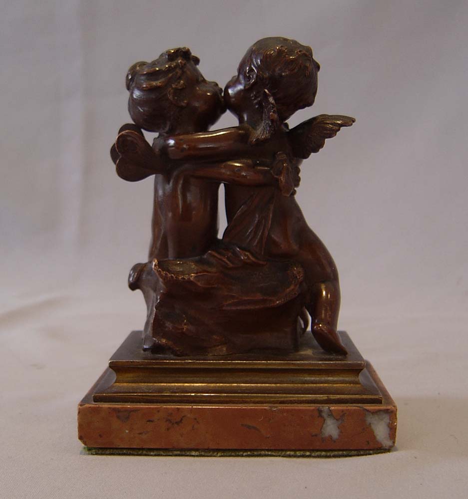 Antique French romantic bronze of winged puttae kissing set on a marble base.