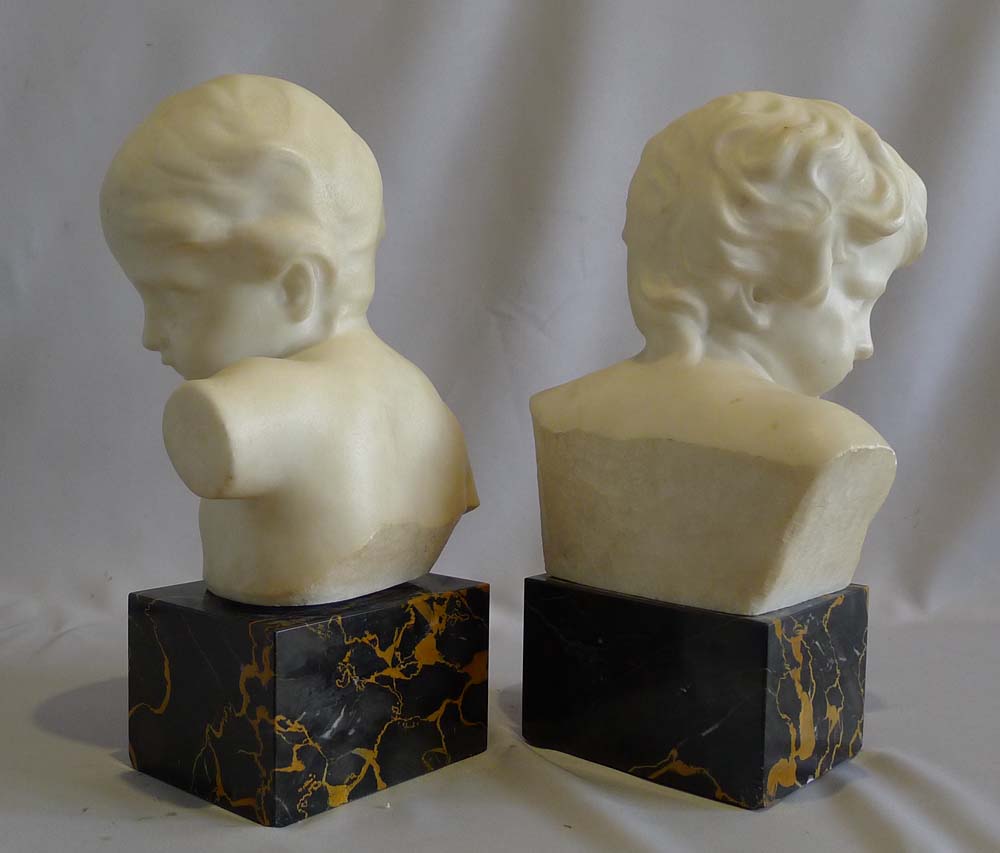 Antique pair of white marble busts of children on variegated marble bases.