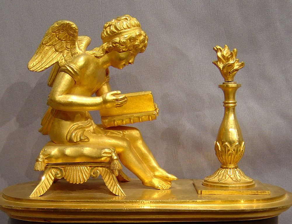 Antique French Empire patinated bronze and ormolu clock of boot shape of Cupid studying.