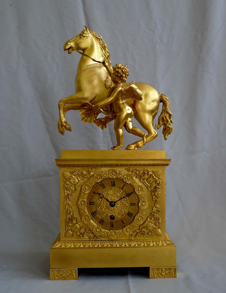 Antique French Empire mantel clock in ormolu of Cupid holding a horse.