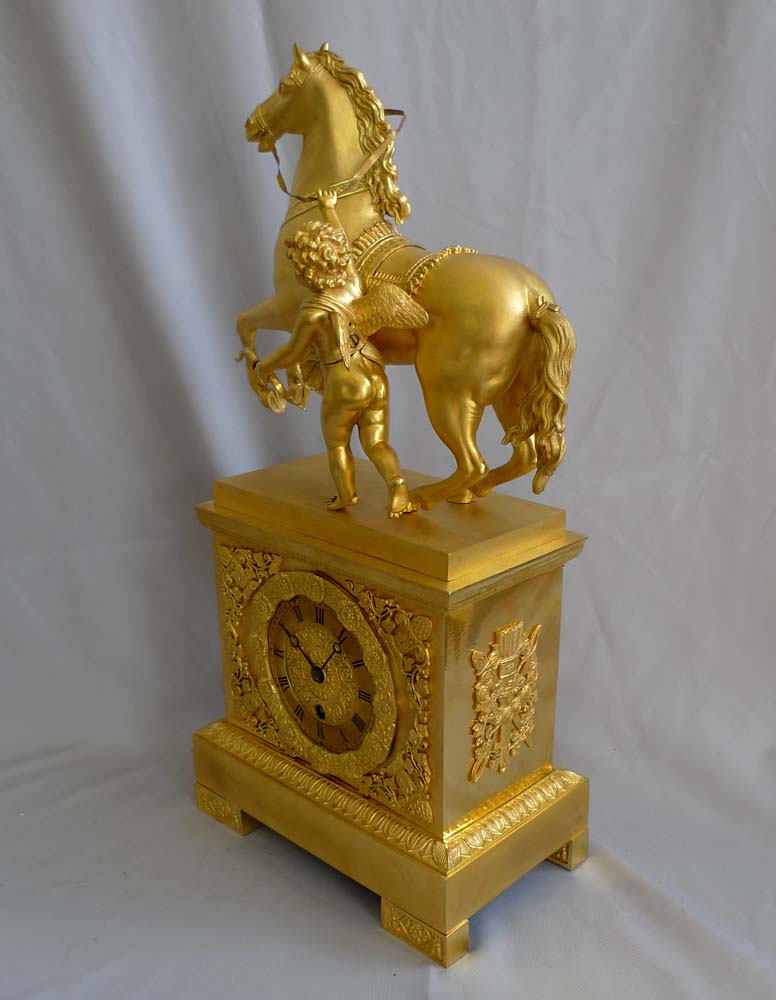 Antique French Empire mantel clock in ormolu of Cupid holding a horse.