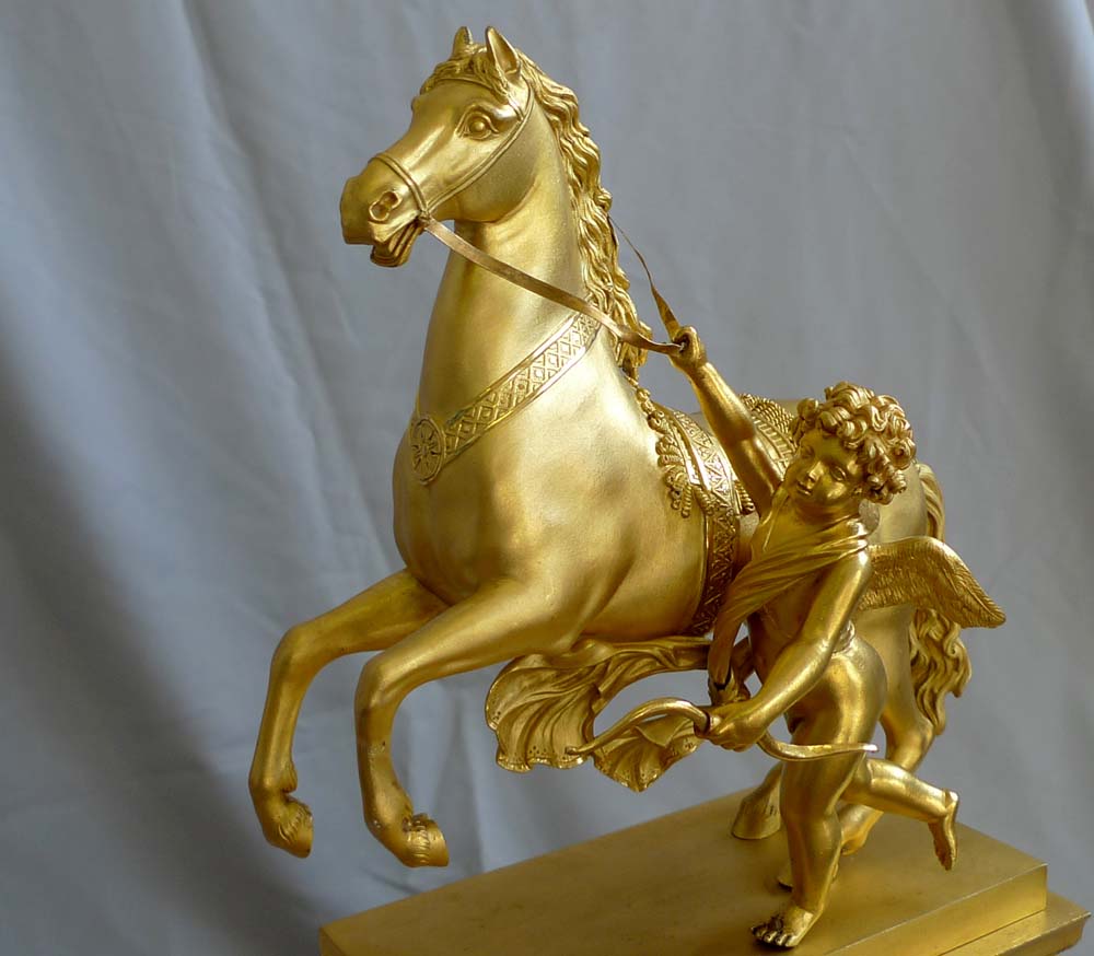 Antique French Empire mantel clock in ormolu of Cupid holding a horse.