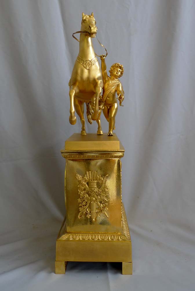 Antique French Empire mantel clock in ormolu of Cupid holding a horse.