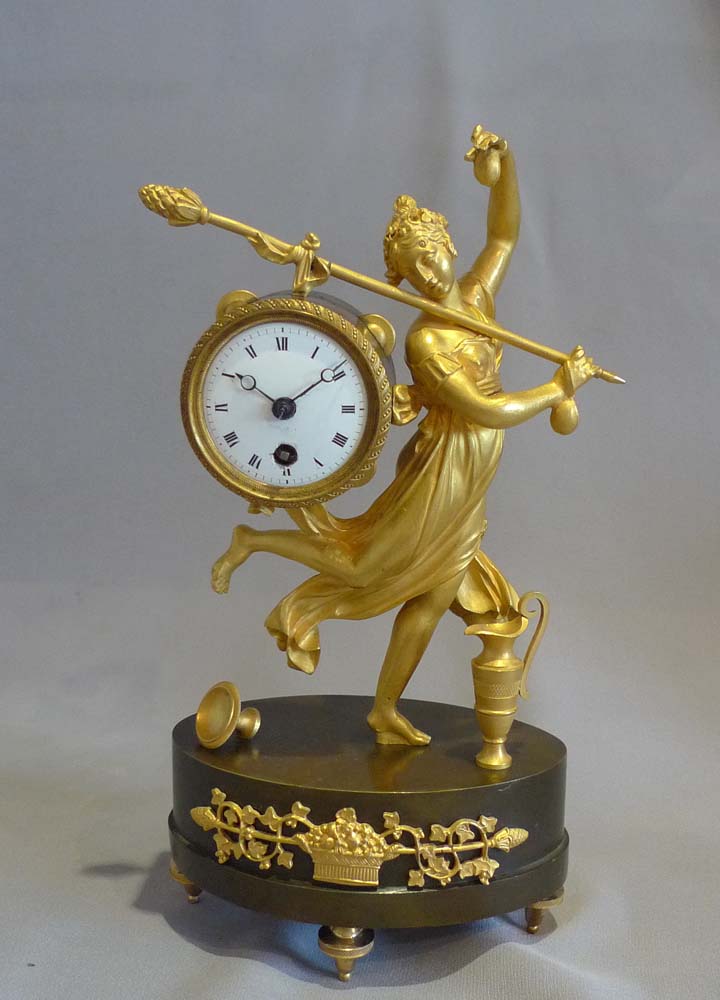 Antique French Empire miniature mantel clock of a dancing baccante in ormolu and patinated bronze.