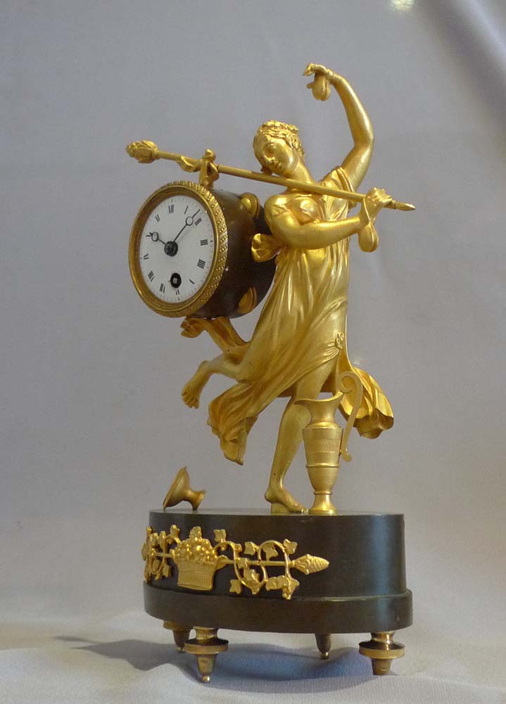 Antique French Empire miniature mantel clock of a dancing baccante in ormolu and patinated bronze.