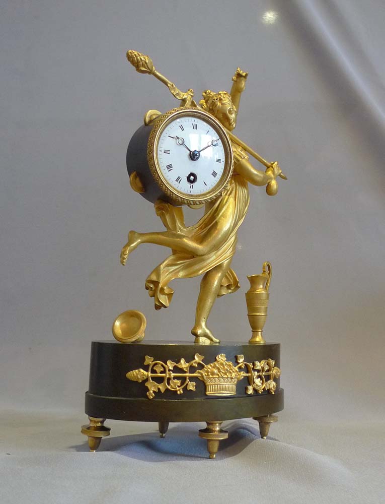 Antique French Empire miniature mantel clock of a dancing baccante in ormolu and patinated bronze.