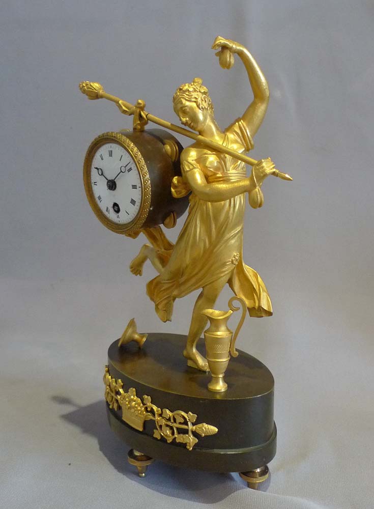 Antique French Empire miniature mantel clock of a dancing baccante in ormolu and patinated bronze.