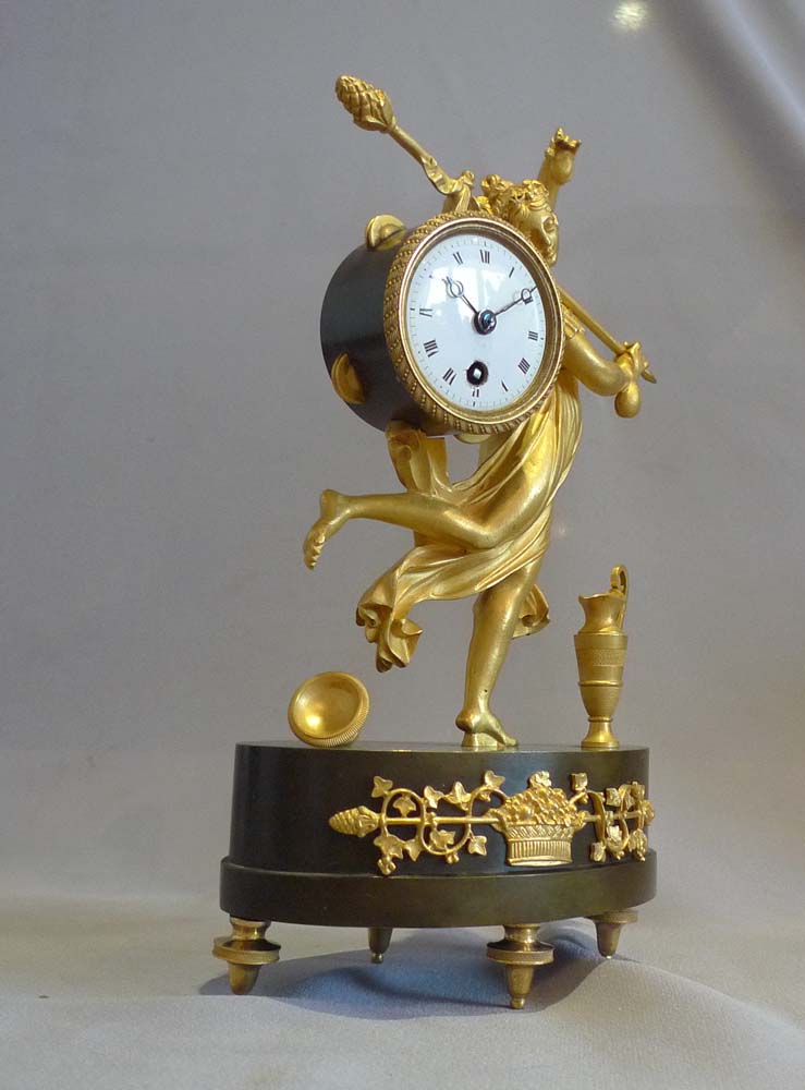 Antique French Empire miniature mantel clock of a dancing baccante in ormolu and patinated bronze.