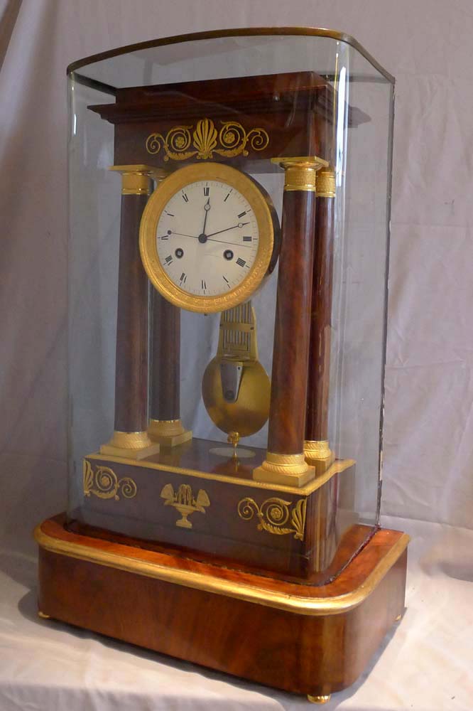 Antique French Empire period, flame mahogany and ormolu mounted musical portico clock.