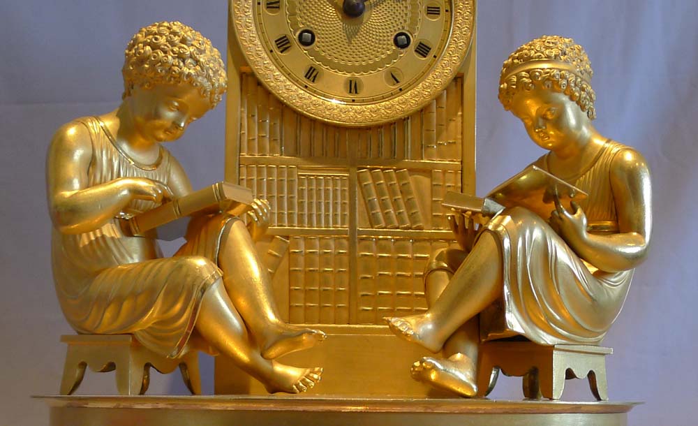 Antique French Empire ormolu library clock of two children reading before a book case