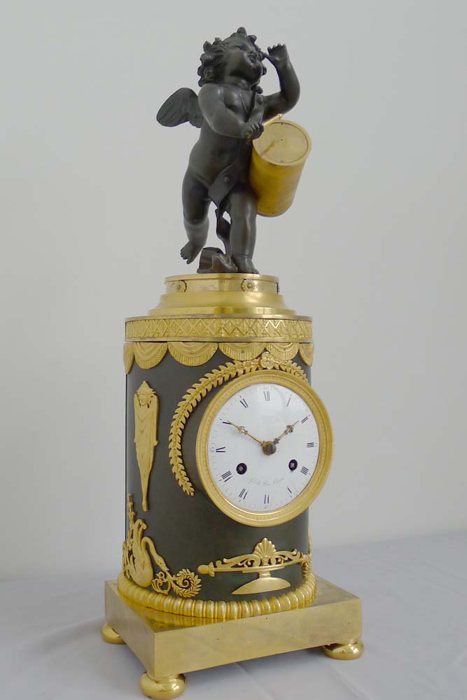 Antique French Ist Empire clock in patinated bronze and ormolu of cupid playing a drum.