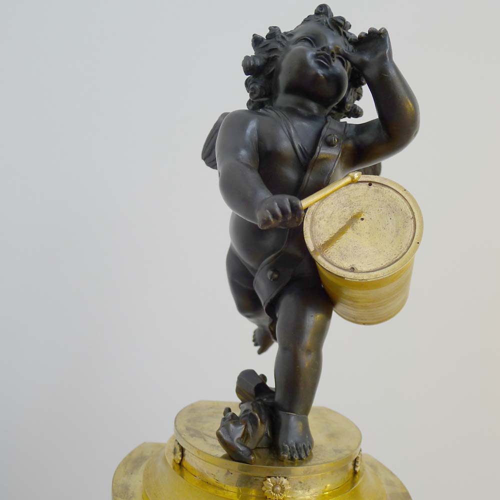 Antique French Ist Empire clock in patinated bronze and ormolu of cupid playing a drum.