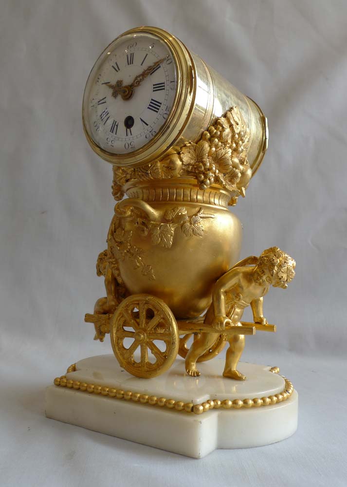 Antique French ormolu clock of two cupids pulling a cart carrying an urn full of grapes.