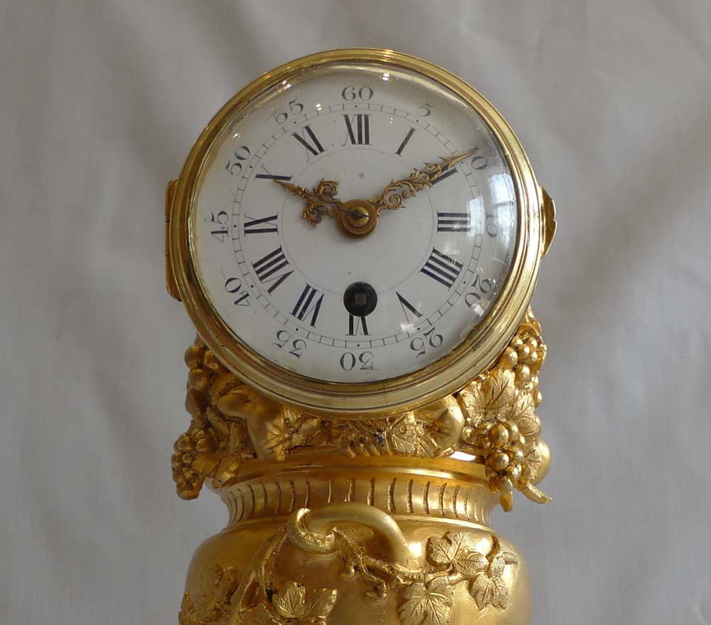 Antique French ormolu clock of two cupids pulling a cart carrying an urn full of grapes.