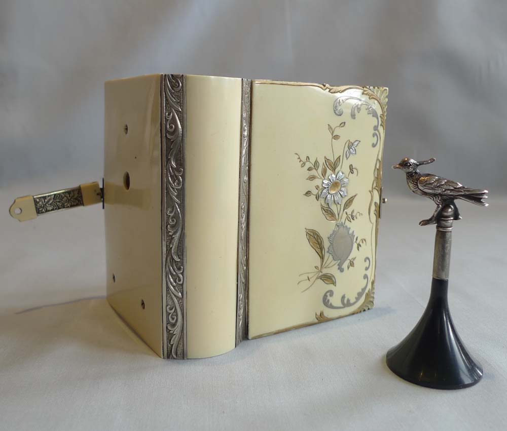Singing bird box in silver and enamelling in book form by Griesbaum.
