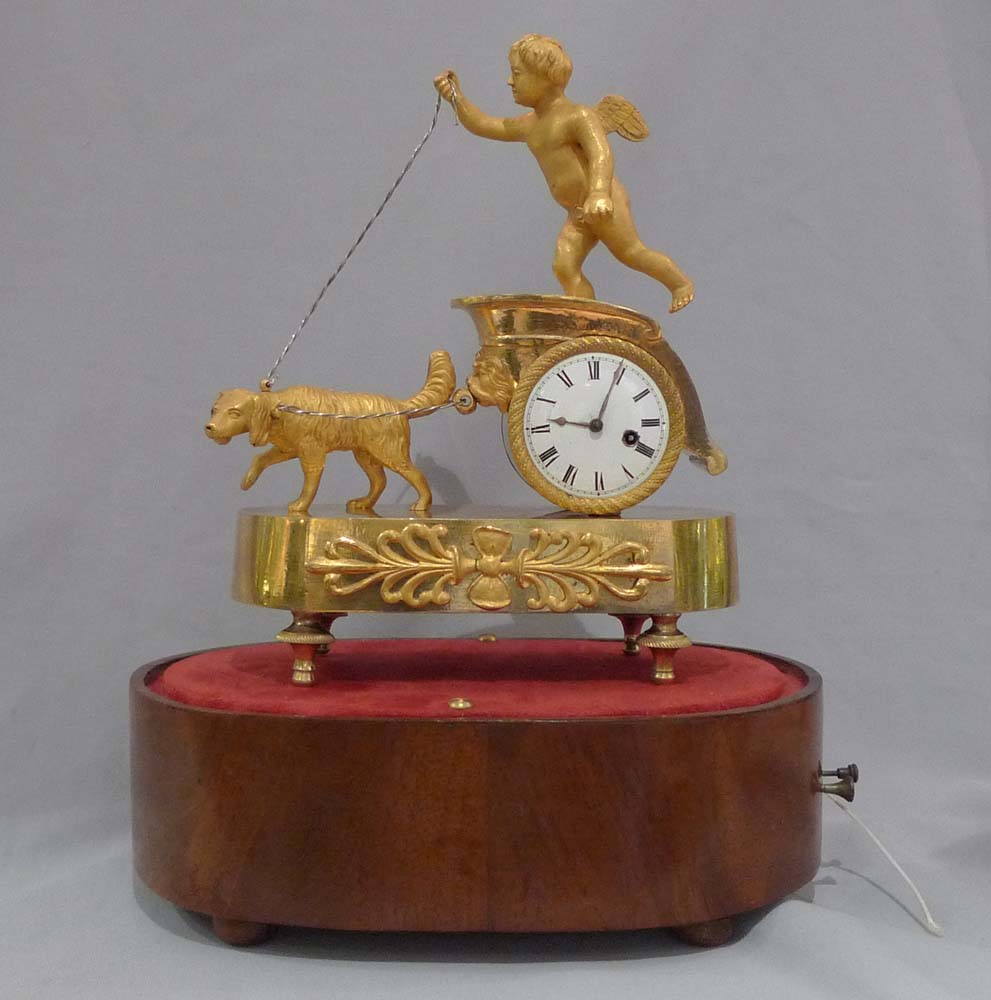 French Empire antique miniature musical mantel clock of dog pulling a chariot.