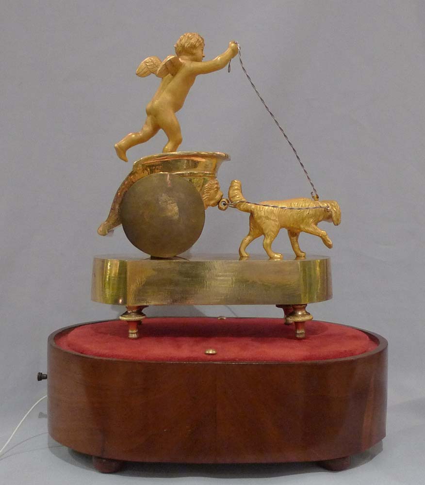 French Empire antique miniature musical mantel clock of dog pulling a chariot.