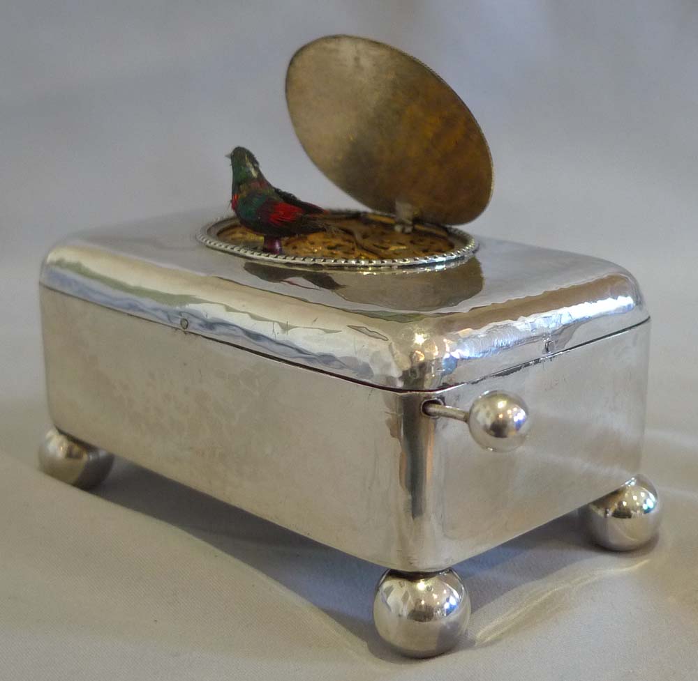 Antique singing bird box in hammered silver case.