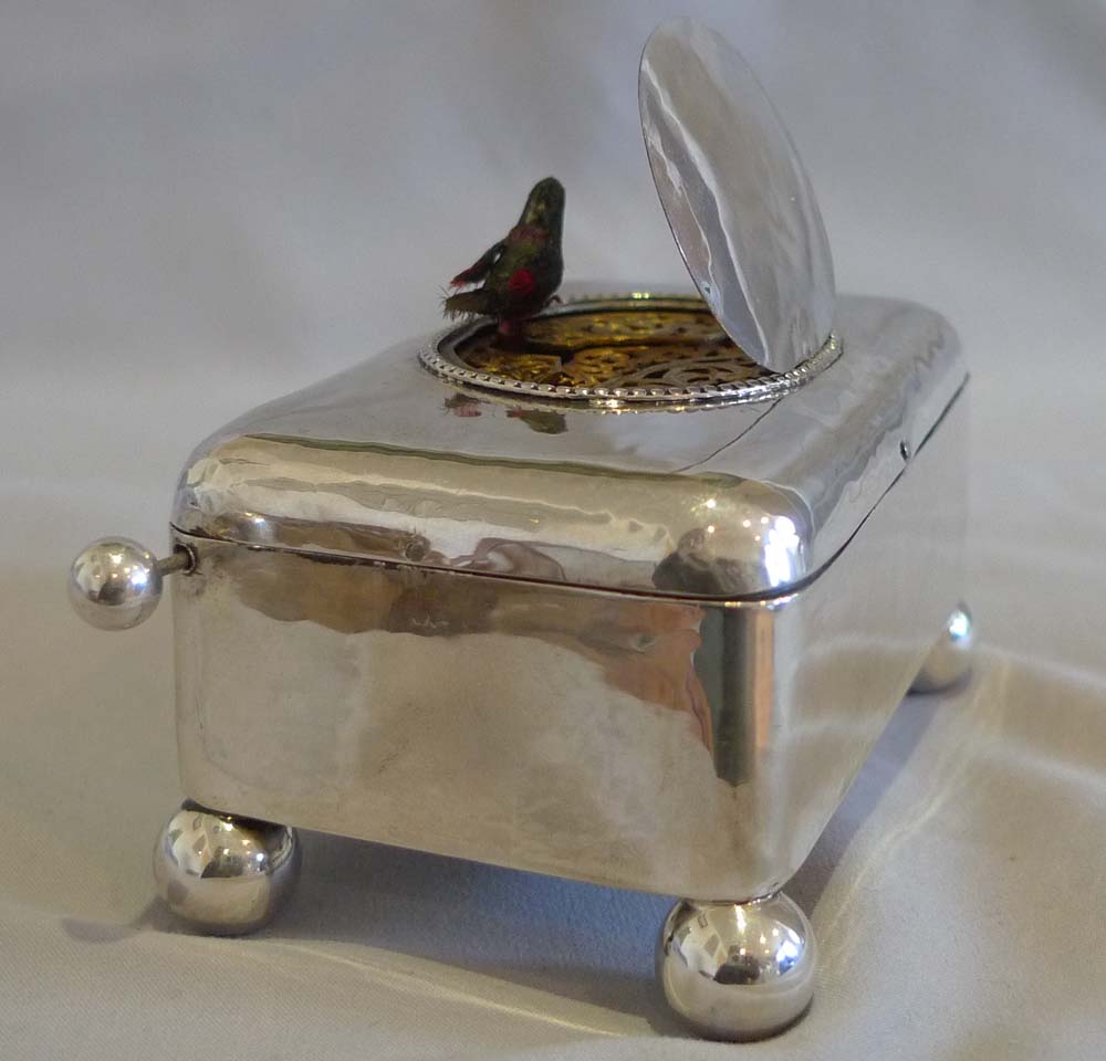 Antique singing bird box in hammered silver case.
