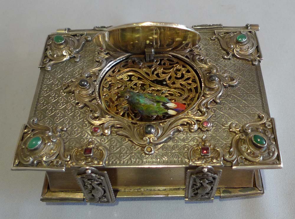 Singing bird box in form of a jewelled book in silver with enamel hand painting.