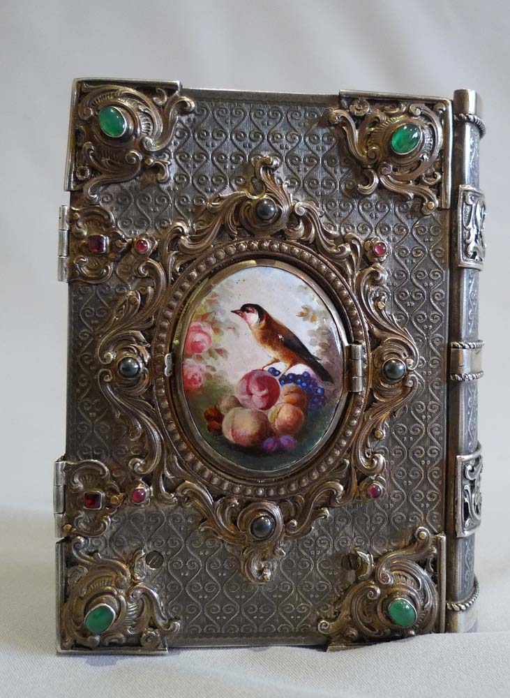 Singing bird box in form of a jewelled book in silver with enamel hand painting.