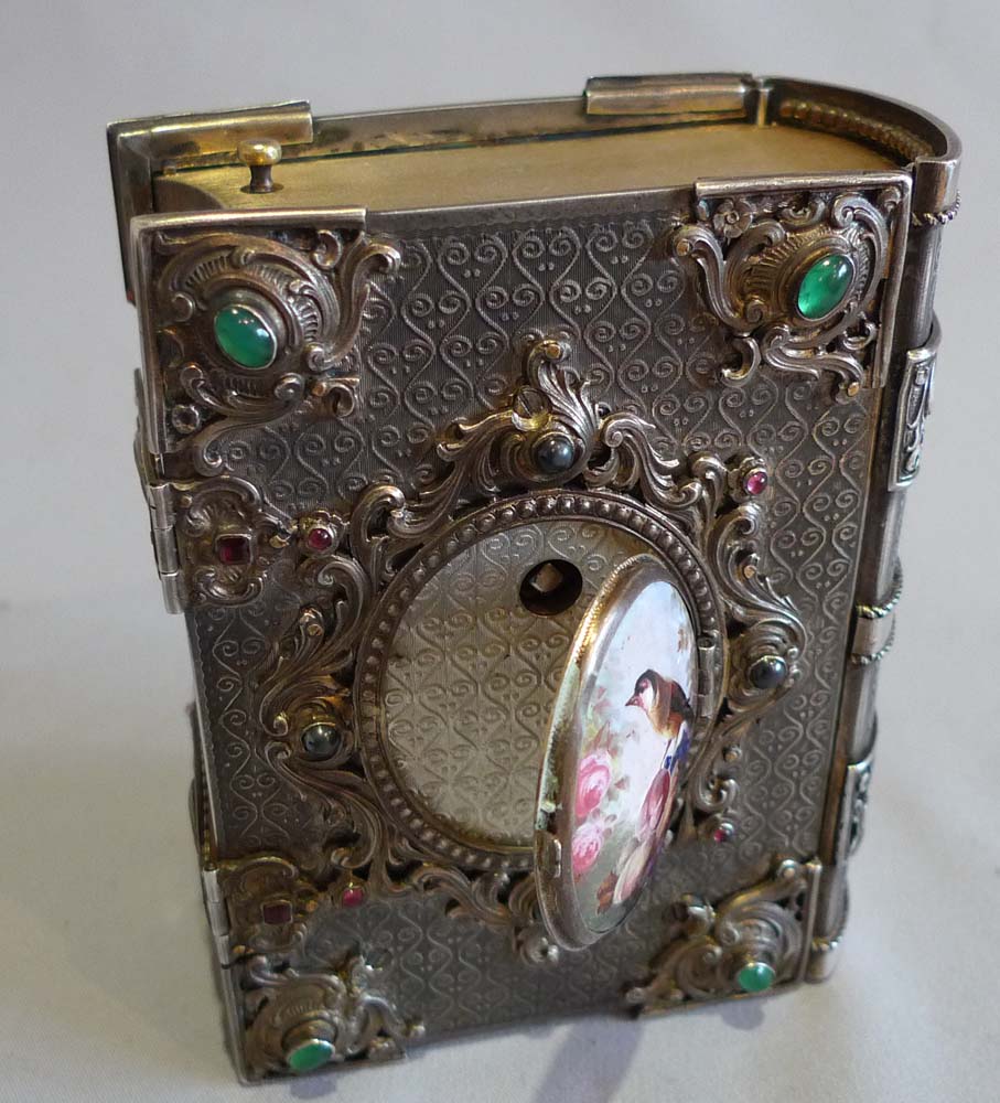 Singing bird box in form of a jewelled book in silver with enamel hand painting.