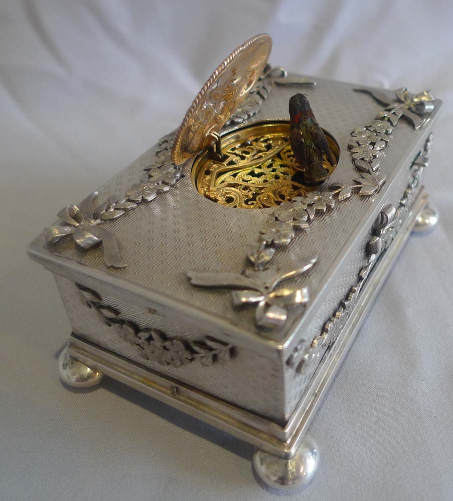 Singing bird box in solid silver with applied swags and bows..