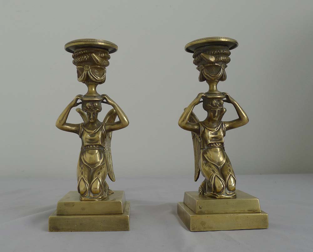Antique pair of English bronze candlesticks of kneeling winged figures.