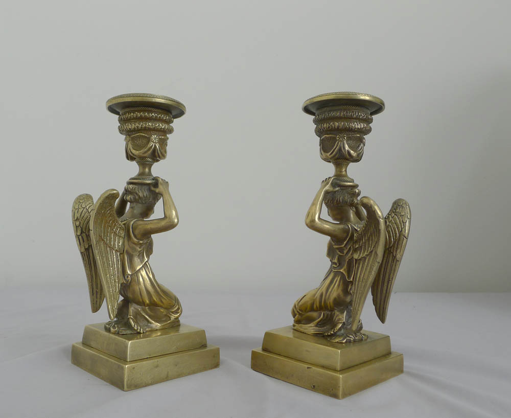 Antique pair of English bronze candlesticks of kneeling winged figures.